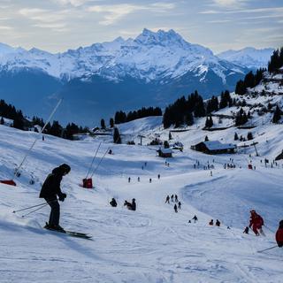 Des skieurs descendent une piste de ski à Villars. [Keystone - Jean-Christophe Bott]
