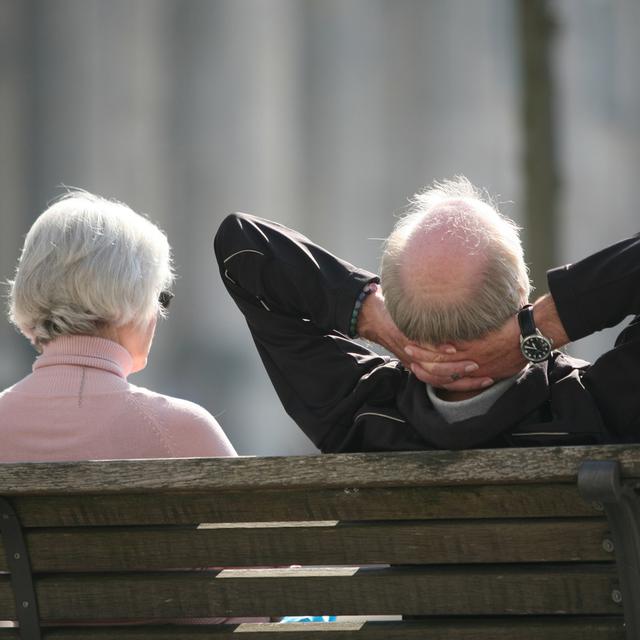 Un couple de jeunes retraités assis sur un banc.
