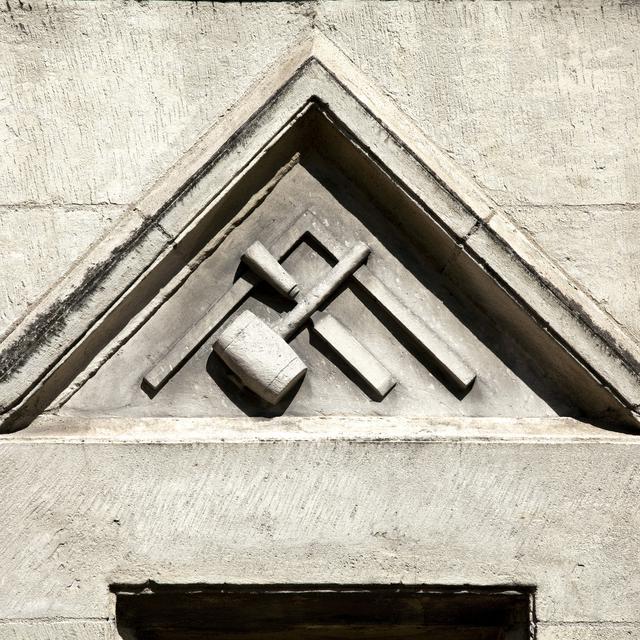 Equerre, maillet et burin, symboles de la franc maçonnerie sur une façade.