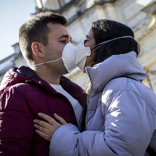Deux jeunes qui s'embrassent avec un masque.