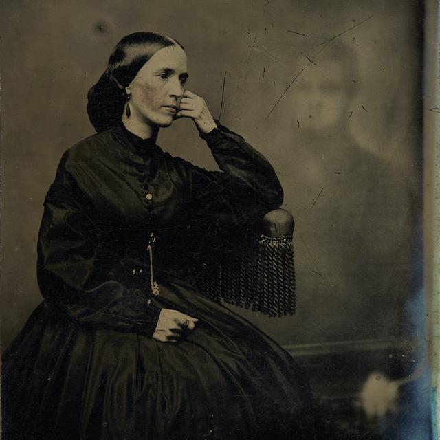Spirit photograph of a woman with a hand on her face with an image of a man in the background (1865).