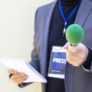 Reporter tenant microphone faisant entrevue avec les médias.